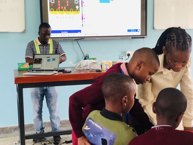 A teacher guiding students through a coding lesson